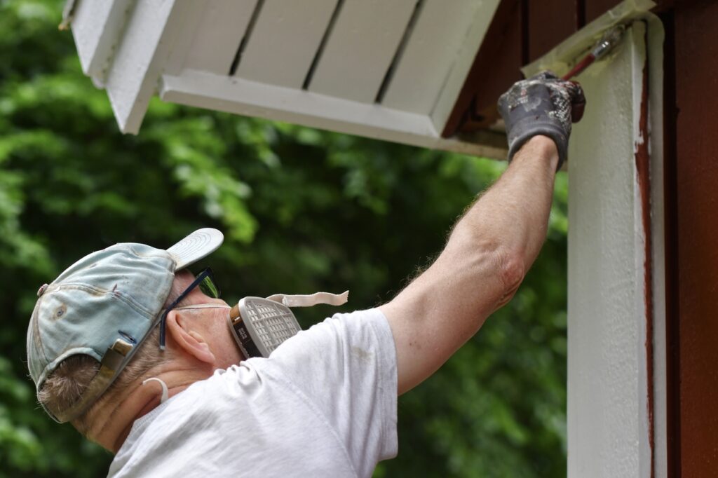 An exterior painting contractor painting a home.