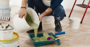 A man is mixing house painting colors in a room. He is preparing the paint for a new project, involving interior painting cost.