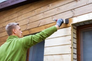 Professional exterior painters carefully paint the upper section of a house's exterior.