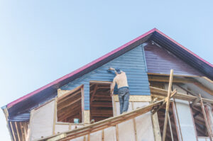 nother individual painting the front of a house high above, highlighting professional painting services.