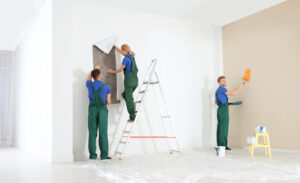 A team of painters is collaborating on a large interior space project, exemplifying the work of commercial painters.