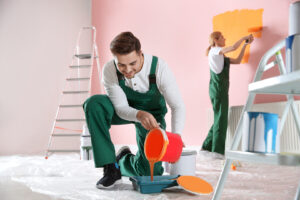 Two painters are engaged in residential painting, working on the interior of a room.