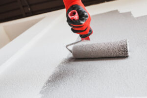 A painting roller applying fresh paint on an exterior wall as part of a commercial exterior painting project.