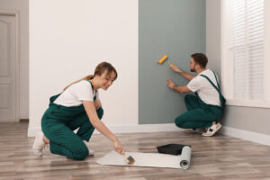 Painters painting a house and putting up wallpaper, depicting the process of painting over wallpaper and enhancing home interiors.