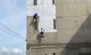 Two painters working on painting a large exterior wall, illustrating the process of commercial exterior painting.