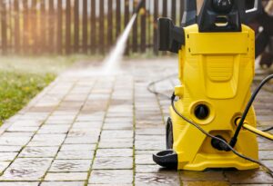 A yellow pressure washing machine on a concrete surface, ready for use in residential pressure washing services.