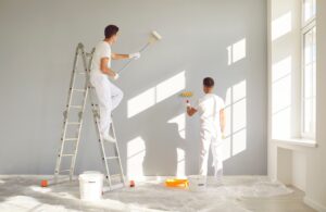 A team of painting contractors Wichita KS painting a wall together.