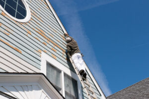 A person painting a roof as part of residential painting services.