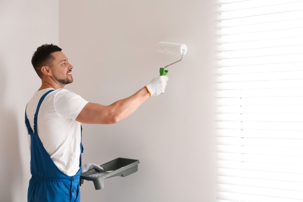 A painter with a roller applying paint, focusing on the process of interior painting.