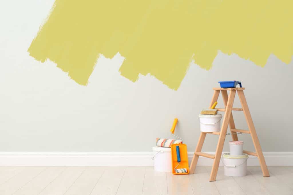 An interior house painter painting a wall half yellow, showcasing the transformation in progress.