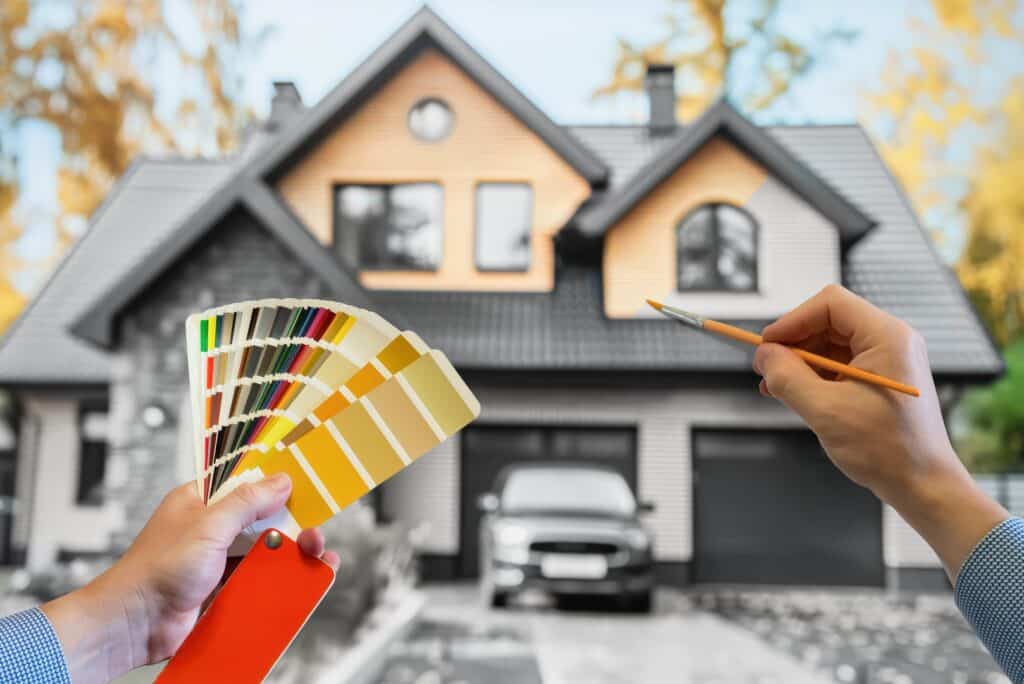 An exterior residential painter selecting from a beautiful color palette in front of the house, holding a brush.