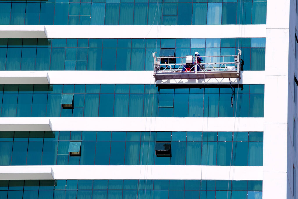 A crew member performs commercial painting on the exterior of a high-rise building, ensuring a fresh, professional look.