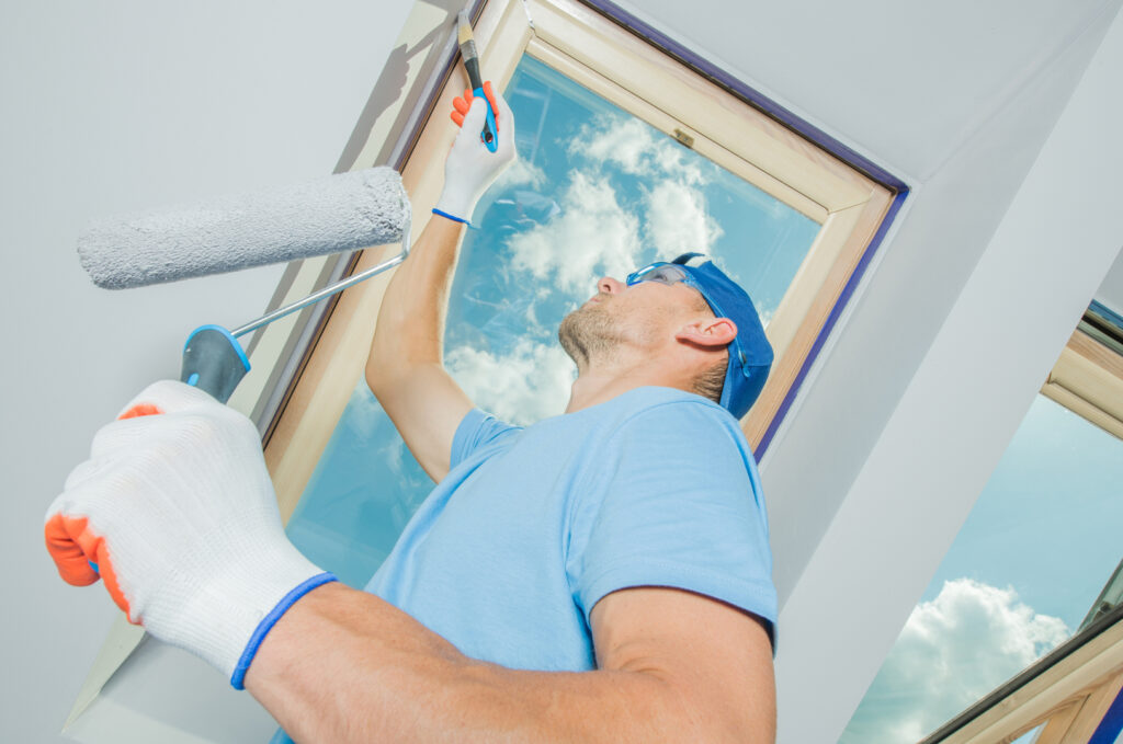 A painter applies fresh paint to an interior window frame, part of a comprehensive commercial painting service.