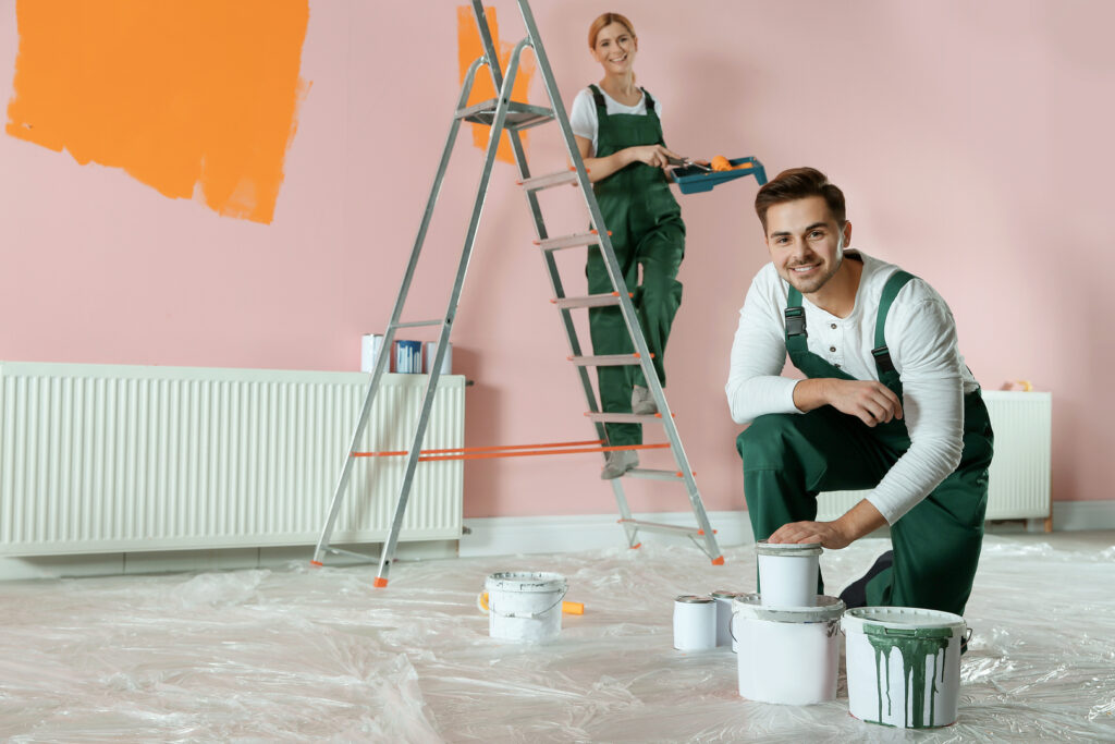 Two painters working together to paint an interior wall in a commercial space, showcasing the benefits of commercial painting services.