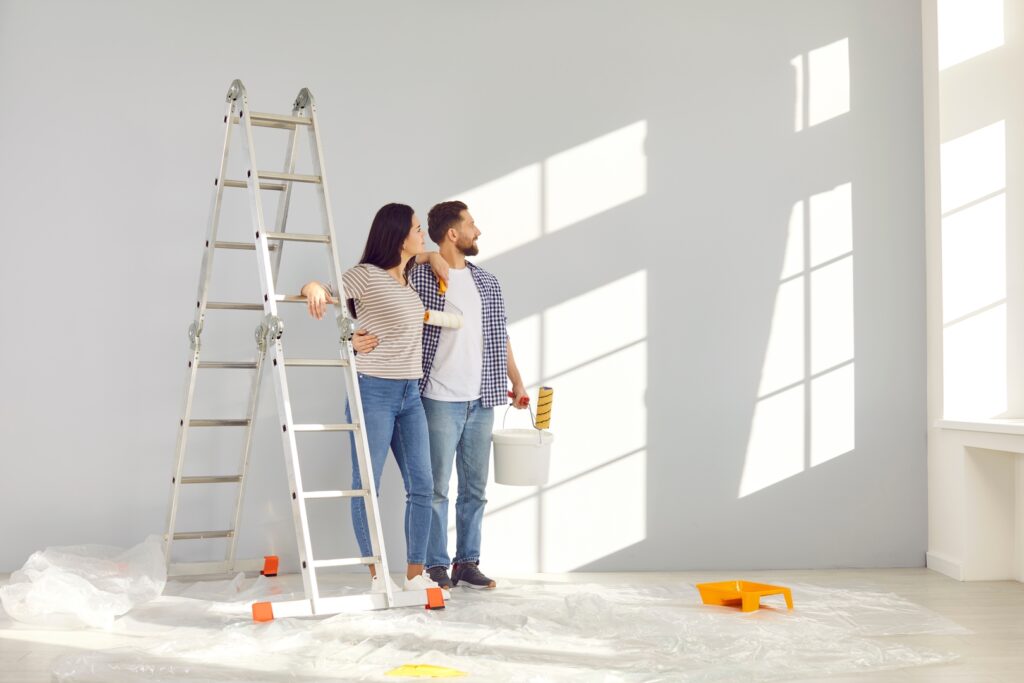 A happy couple painting their room together, selecting mood-boosting colors to create a cheerful environment.