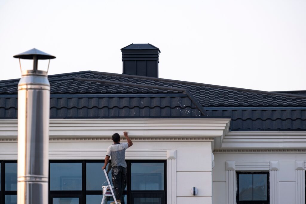 A painter painting a house exterior, showcasing the process of exterior painting.