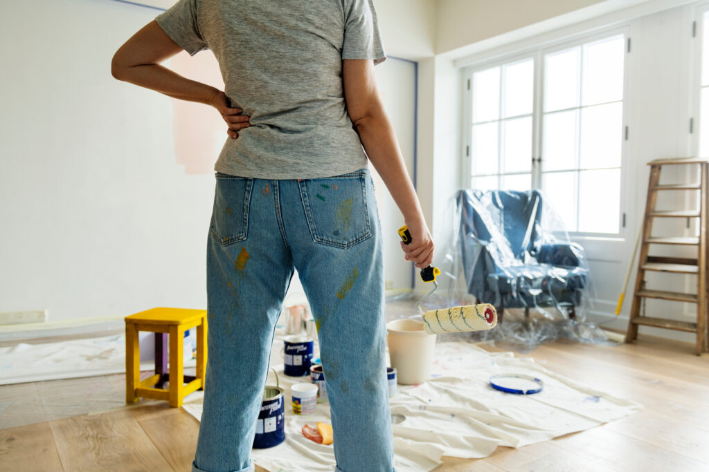 A person stands with a paint roller preparing to work on an interior wall, illustrating house painting in Wichita.