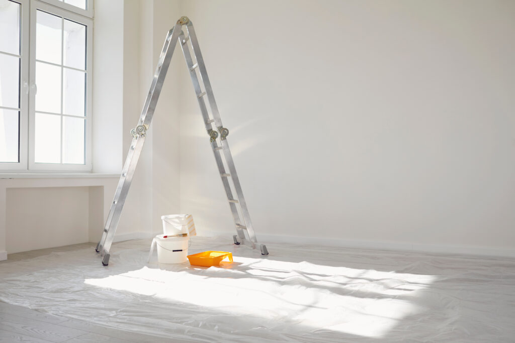 A setup for interior painting in Wichita KS in Wichita, with a ladder, paint trays, and buckets in a clean, well-lit room.