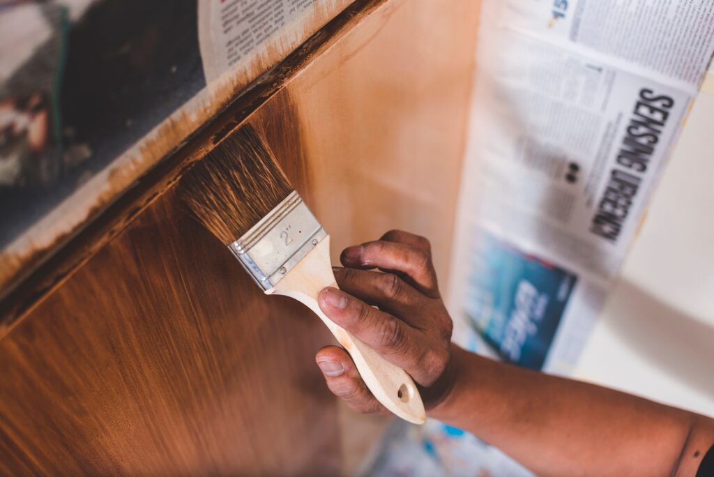 A close-up of a painter in Wichita applying a wood stain with precision.