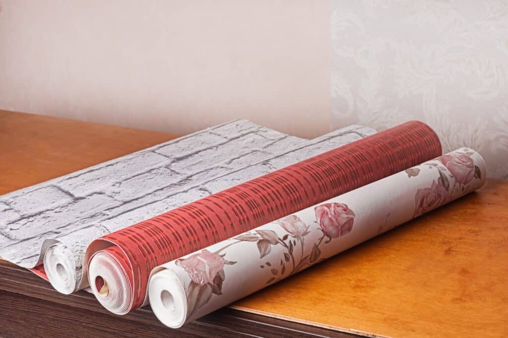 Different wallpaper rolls, showing textures and patterns, an essential part of deciding how to paint over wallpaper successfully.