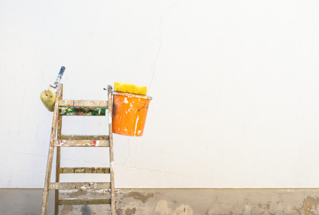 A bucket and ladder prepared for a commercial building painting project.