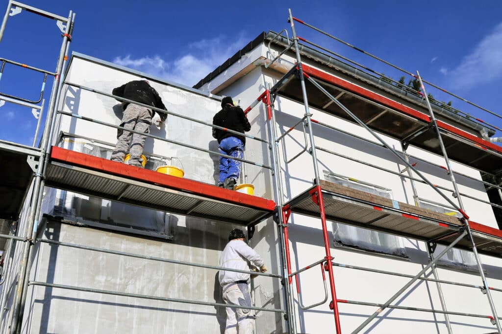 Painters on scaffolding working on a building exterior, representing painting contractors Wichita KS at work.