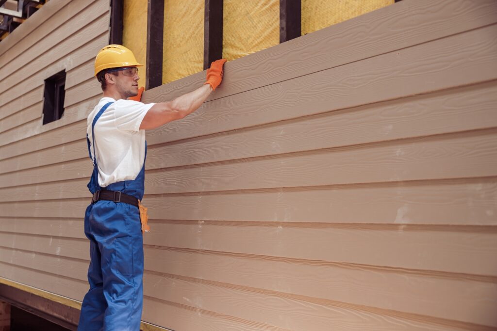 A contractor installing siding panels, exemplifying skilled siding contractors in Wichita KS.