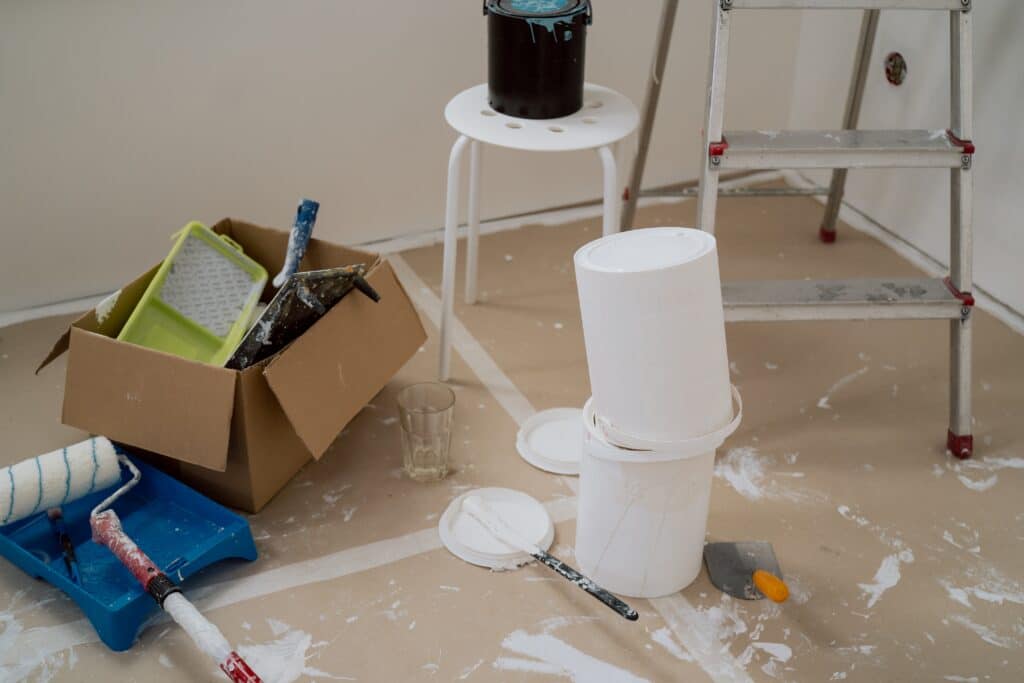 Painting and renovation tools scattered on the floor, showing the disorganized mess that can result from DIY efforts, emphasizing the value of hiring professional siding contractors for a clean and hassle-free project