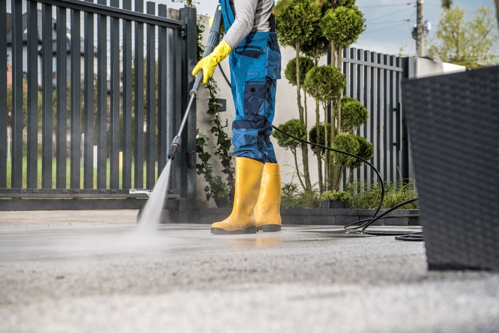 A working man with an overall applying power washing to a property, enhancing the importance of its protection.