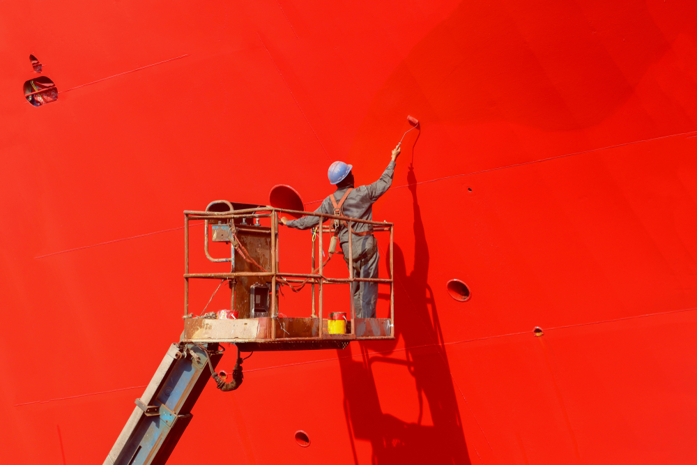 Professional painter working on a large red surface using a lift, showing how expert commercial painting services that transform businesses. 