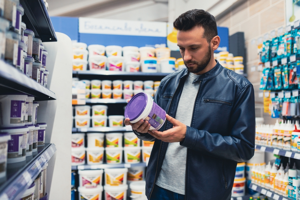 A man carefully selecting paint in a store—because choosing the right commercial painters starts with quality materials. The right team ensures durability, precision, and a professional finish that enhances your business space.