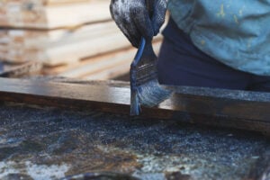 An exterior painter paints a paint board with a brush.