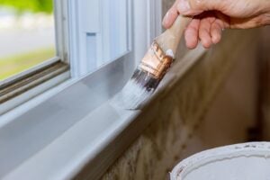 A painter from one of the professional painting services in Wichita Kansas painting a window edge.