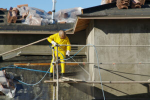 A residential painting contractor pressure washing the exterior walls of a home before painting begins.