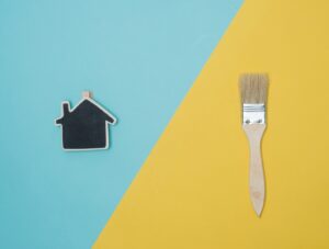 An artistic diurnal image showcasing a split background in two colors; on one side, a detailed figure of a house, and on the other, a paintbrush, representing SATISFACTION GUARANTEED through creative expression.