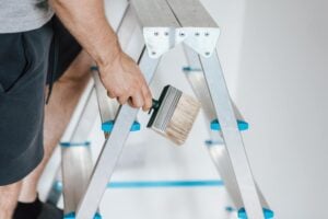 One of the painters near me climbing a ladder to paint a wall.