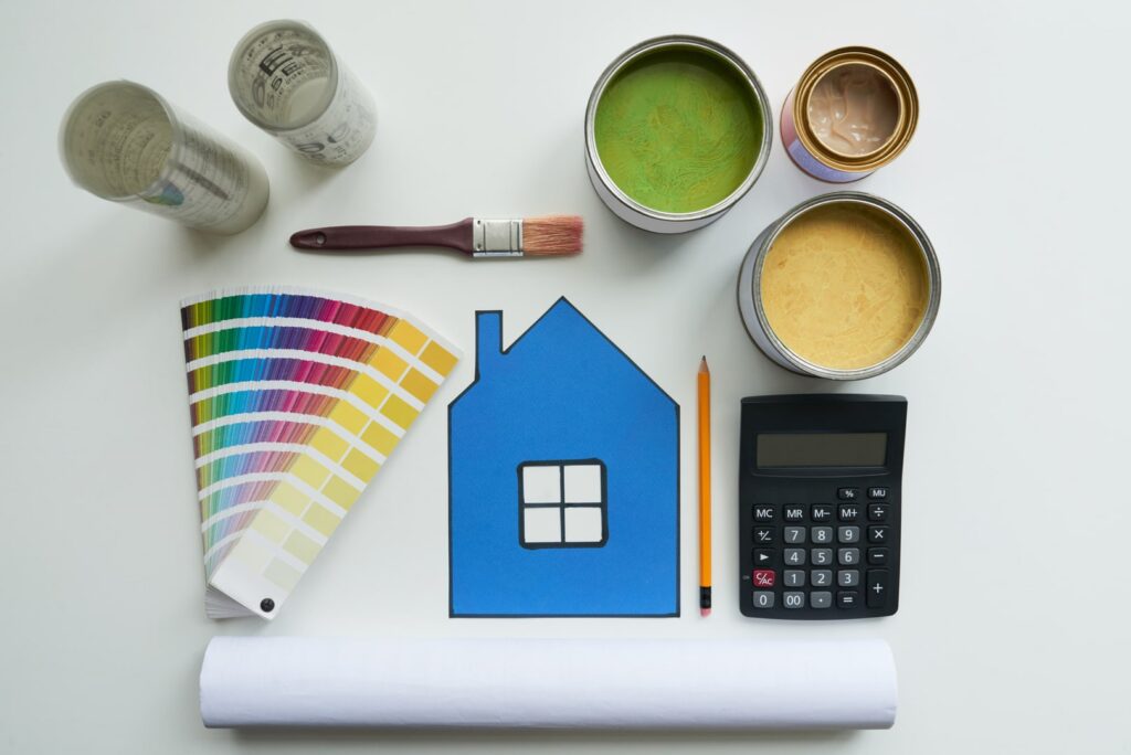 A creatively arranged display of paint cans, brushes, and a wooden figure of a house against a backdrop of a vibrant color palette, highlighting the aesthetic and functional aspects of paint ratings. This artistic representation serves to illustrate the beauty and quality of paints available, guiding consumers in their decision-making based on paint ratings.