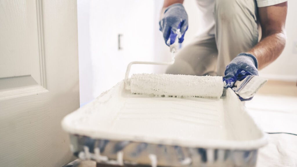 Painting contractor preparing paint with a roller.