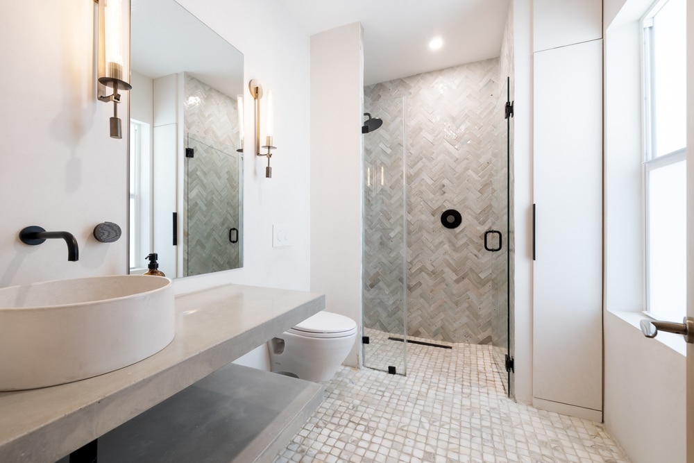 Modern bathroom featuring a vessel sink, floating concrete vanity, and herringbone tile shower—an example of unique home renovations that combine style and function.