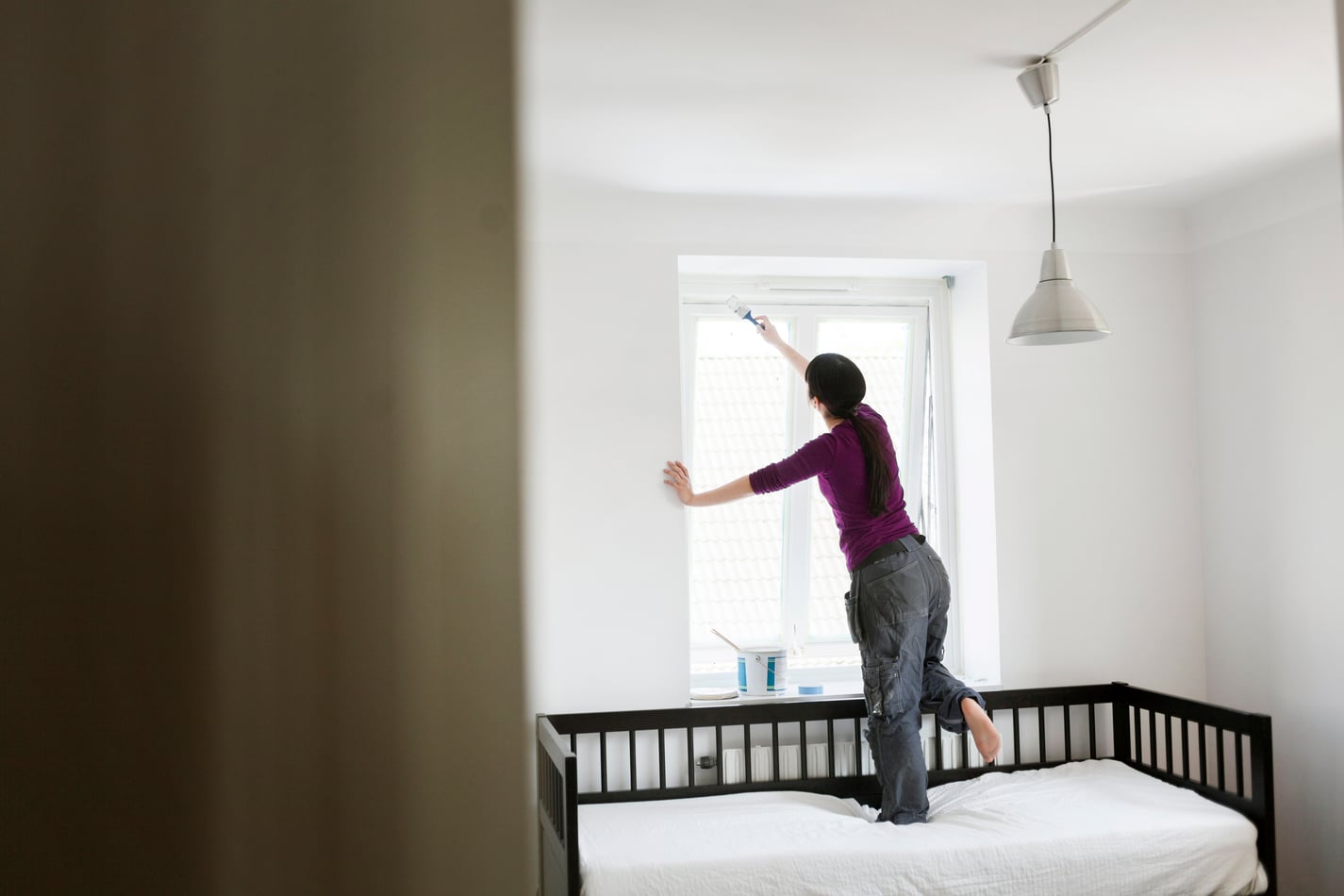 A woman who has opted for DIY painting instead of performing an online search for 'painters near me.'