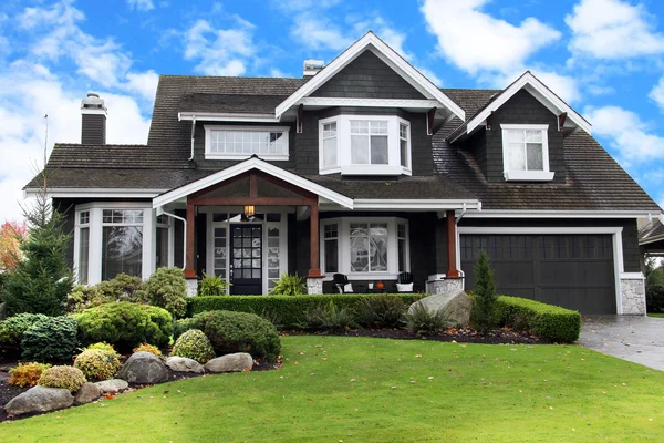 House with dark gray siding, crisp white trim, and warm wood accents by an exterior painter in El Dorado, KS.